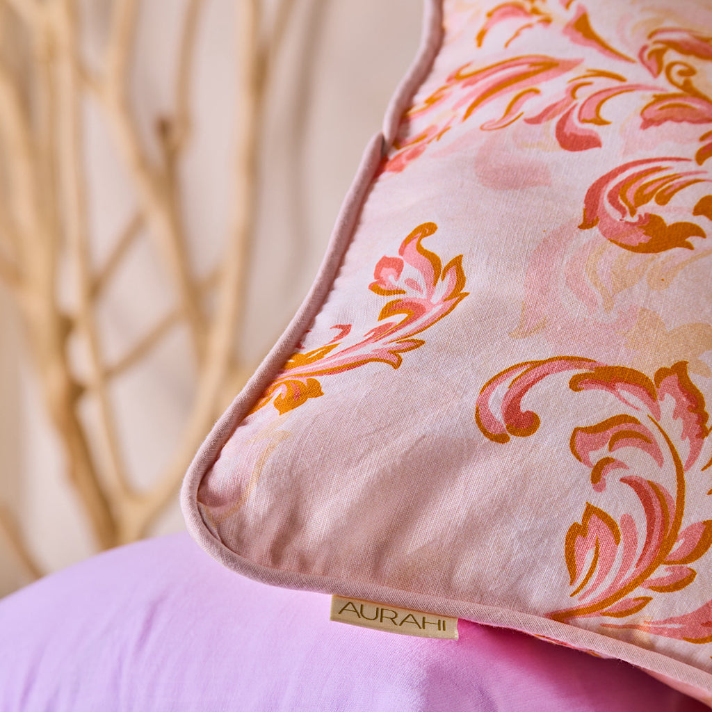 Decorative pillow with floral pattern and 'AURAAHI' branding on a blurred background