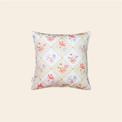 A floral cushion cover made from hemp fabric, featuring a delicate diamond lattice pattern filled with colorful watercolor wildflowers in pink, orange, and purple, presented against a plain off-white background.