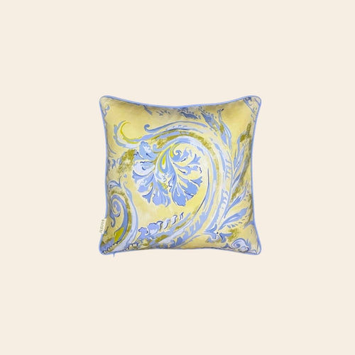 A square cusion cover made from hemp fabric with a yellow and blue ornate floral pattern on a plain background.