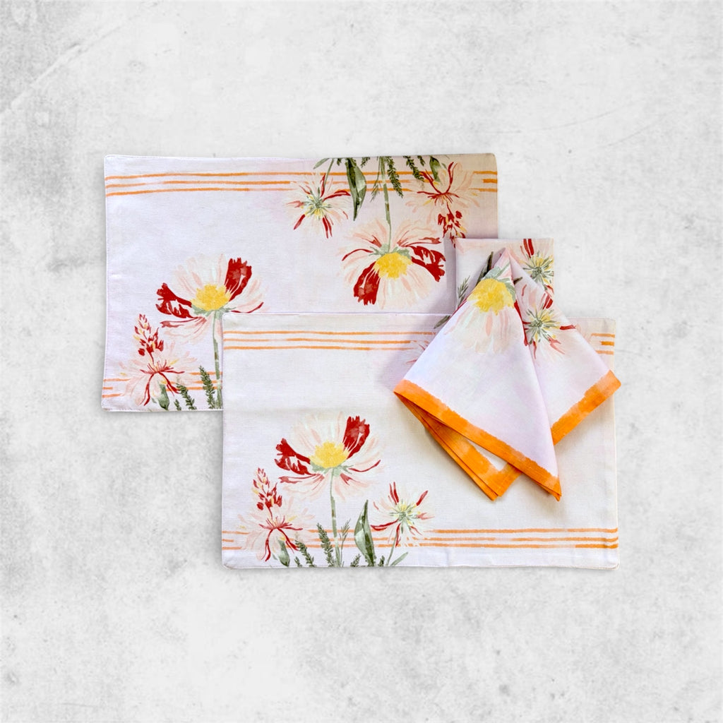 A set of two artisanal Table Placemats featuring hand-painted red and yellow botanical florals and orange stripes, displayed with a matching folded cloth napkin.